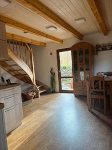 Habitación grande con escalera y cocina con suelo de madera. en Chata U lesa, en Svoboda nad Úpou