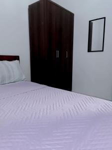 Schlafzimmer mit einem weißen Bett und einem Holzschrank in der Unterkunft Sleep, Eat, Relax with Serenity in Lucena