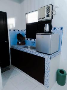 a kitchen counter with a sink and a microwave at Sleep, Eat, Relax with Serenity in Lucena