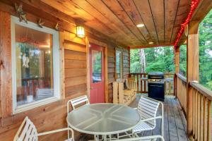Un porche de una cabaña con una mesa y sillas. en Forested Coffman Cove Cabin with Wood-Burning Stove!, en Coffman Cove