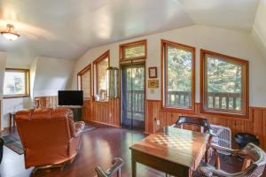 a living room with a table and chairs and windows at Forested Coffman Cove Cabin with Wood-Burning Stove! in Coffman Cove