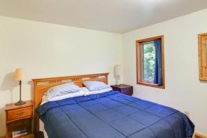 a bedroom with a blue bed and a window at Forested Coffman Cove Cabin with Wood-Burning Stove! in Coffman Cove