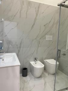 een witte badkamer met een wastafel en een toilet bij B&B Kemare Suites in Barletta