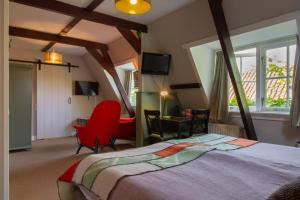 a bedroom with a large bed and a red chair at Hotel De Koegelwieck Terschelling in Hoorn