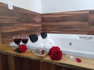 a bath tub with two glasses of wine and roses at Recanto KAIRÓS in Visconde De Maua