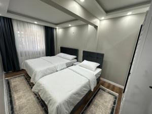 two beds in a room with white sheets and pillows at İstanbul Airport House Tayakadın in Arnavutköy