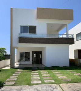 Casa blanca con balcón y césped en Reluz Tranquility melhorcasaaracaju, en Aracaju