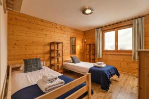 two beds in a room with wooden walls at Chalet Elbaz - Swiss Chalet with breathtaking views in La Tzoumaz