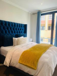 a bedroom with a large bed with a blue headboard at MarbleNights Bedford in Johannesburg