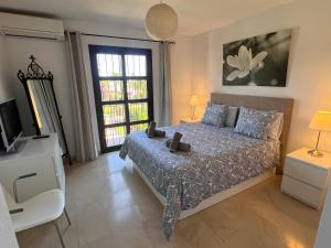 a bedroom with a bed and a tv and a window at Adosado en residencial in Mijas Costa