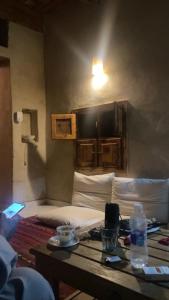 Siwa desert home في سيوة: غرفة بسرير وطاولة مع زجاجة ماء