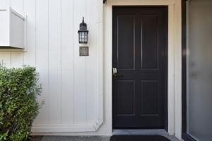 a black door on a white house with a lamp at Getaway Suite at Silverado in Napa in Napa