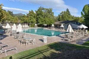 una piscina con sillas, mesas y sombrillas blancas en Getaway Suite at Silverado in Napa, en Napa