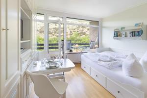 a white bedroom with a bed and a table and chairs at Dünenperle in List
