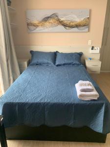 Un dormitorio con una cama azul con toallas. en Stay GRU - Loft 2 Completo próx GRU airport - Guarulhos en Guarulhos