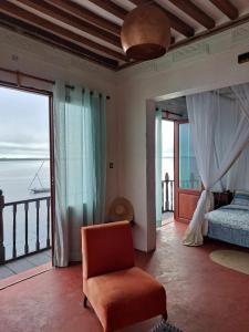 a bedroom with a bed and a chair and a balcony at Pwani House - Lamu Seafront in Lamu