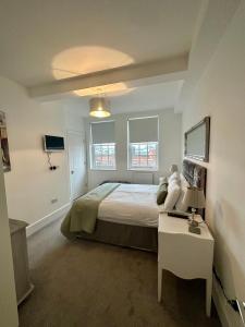 Un dormitorio con una cama y una mesa y dos ventanas. en CC - Central Location Top Floor 2 Bed Deluxe Modern Apartment, en Stratford-upon-Avon