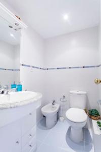 a white bathroom with a toilet and a sink at The Beach Apartment in El Puig