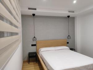 a small bedroom with a bed and two pendant lights at Fernando Quero 21 in Andújar