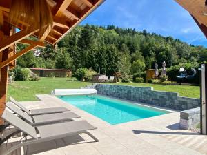 een zwembad met 2 ligstoelen in de tuin bij Gîte Chalet avec bain nordique et piscine 11 pers Hautes Vosges in Plainfaing