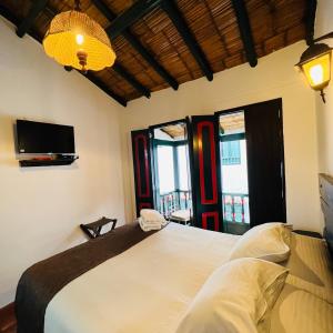 a bedroom with a bed and a tv and windows at Hotel Boutique Samay in Duitama