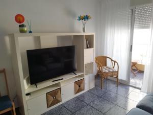 una sala de estar con TV en un centro de entretenimiento blanco en Capitanía frente al mar, en Puerto de Mazarrón