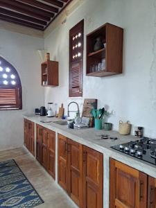 a kitchen with wooden cabinets and a counter top at Pwani House - Lamu Seafront in Lamu