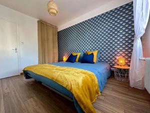 a bedroom with a bed with a blue and yellow blanket at Rés. Marie Galante, Lac du Der 