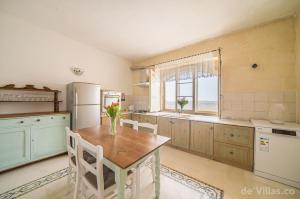 cocina con mesa, nevera y ventana en Ta' Lonza Farmhouse, en Għarb