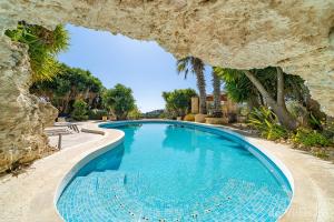 a swimming pool framed by a rock formation at Lunzjata Maisonette in Victoria