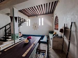 a living room with a wooden table and stairs at Pwani House - Lamu Seafront in Lamu