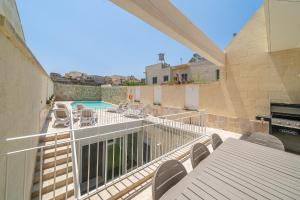 een balkon met een tafel en stoelen en een zwembad bij Ta' Spiru in Munxar