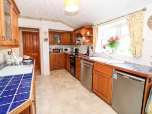 a kitchen with wooden cabinets and a large window at Appletree Cottage in Richmond