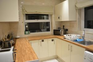 a kitchen with white cabinets and a sink and a window at Large Ensuite room in Oxford