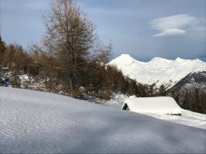 a snow covered building on a snow covered slope with mountains at La Maison du Gorret in Aosta