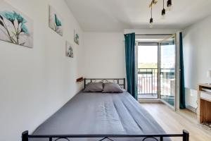 ein Bett in einem Schlafzimmer mit einem großen Fenster in der Unterkunft Le Cli’Chic Family in Clichy