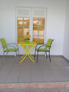 una mesa amarilla y 2 sillas en un patio en Les Colibris, en Sainte-Anne