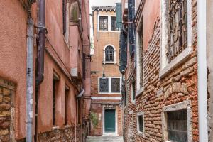 alejka pomiędzy dwoma budynkami z zielonymi drzwiami w obiekcie The Silk House w Wenecji