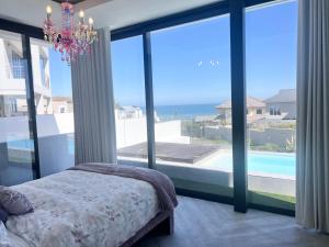 a bedroom with a chandelier and large glass windows at Villa Grace in Cape Town