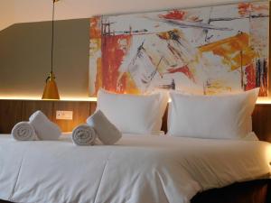 a bedroom with a white bed with a painting on the wall at MIK Hotel Korça in Korçë