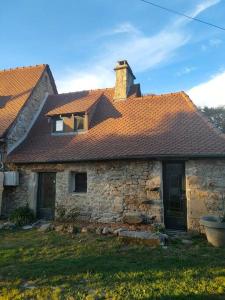 een oud stenen huis met een bruin dak bij La maisonette de Raphaël in Saint-Mamet-la-Salvetat