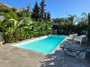 a swimming pool with chairs and plants in a yard at Stylish Voula Apartment with pool close to Kavouri Beach in Athens