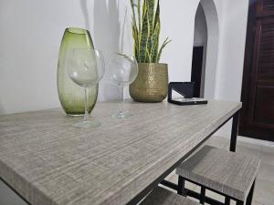 deux verres à vin et un vase sur une table dans l'établissement The Farmhouse Apartment, Junction, Saint Elizabeth, 