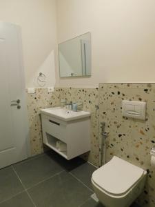 uma casa de banho com um WC, um lavatório e um espelho. em MIK Hotel Korce em Korçë