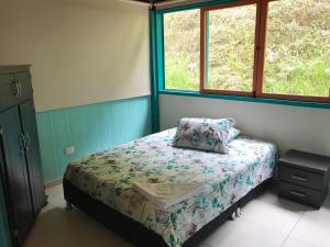 een kleine slaapkamer met een bed en 2 ramen bij Reserva Natural Finca La Cabaña in Dosquebradas