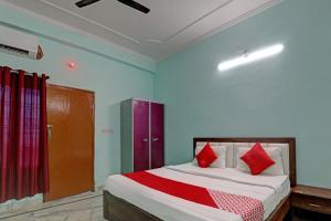 Super OYO Flagship Siddharth Inn في لاكناو: غرفة نوم بسرير ومخدات حمراء