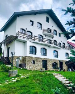 a large white building with a balcony on top of it at Pensiunea Casa Ancutei in Ranca