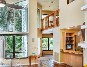 a living room with a staircase and large windows at Beach Paradise Getaway - 200ft from Beach! in Sebastian