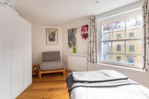 a bedroom with a bed and a chair and a window at Bright & Quirky 3BD Home - Wellington Terrace! in Bristol