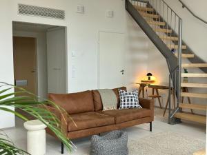 sala de estar con sofá marrón y escalera en Cozy Design Loft next to Metro en Helsinki